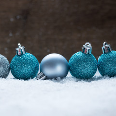 Christbaumkugeln im Schnee vor Holzhintergrund