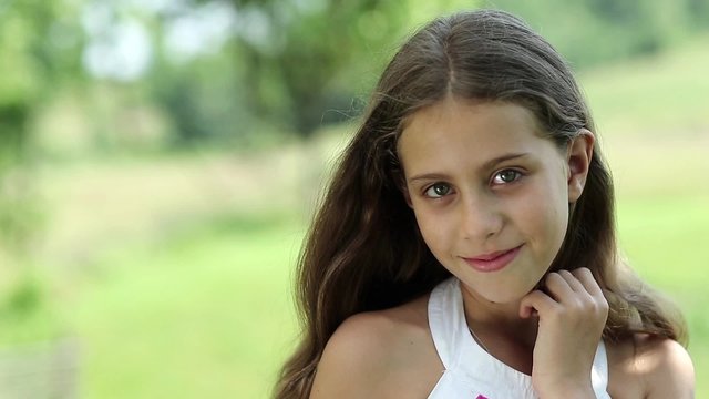 Pretty girl with long hair looks at the camera. Attractive girl looking at the camera, green background
