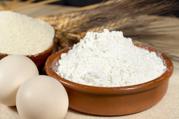 Chicken eggs beside wheat flour, breadcrumbs and wheat spikes. Staple foods.