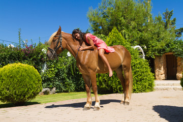 Beautiful young brunette with red dress and her brown-blond horse