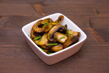 Baked mushrooms on square bowl on wooden table