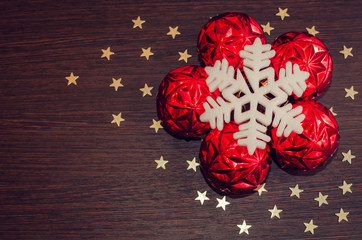 White snowflake and red xmas baubles on brown wooden background with stars. Merry christmas. Winter holidays. Xmas theme. Happy New Year. Blurred background.