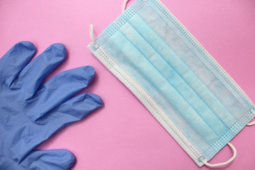 Sterile surgical glove and protective mask on pink background