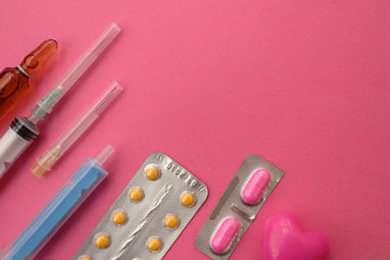Syringe, needle, ampule and pills on pink background - medicine concept