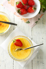 Creme brulee dessert with fresh strawberries and mint leaves, on color wooden background