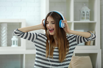 Woman listening music in headphones in room