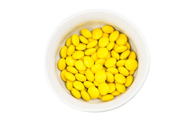 Overhead view bowl of yellow chocolate candy in white background