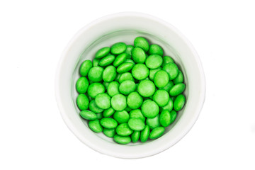 Overhead view bowl of green chocolate candy in white background