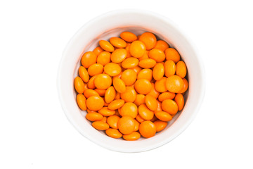 Overhead view bowl of orange chocolate candy in white background