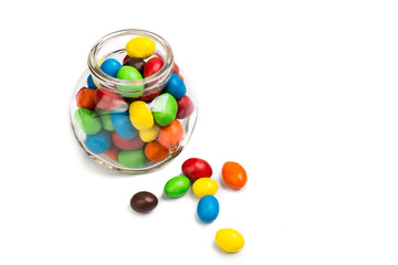 Fototapeta na wymiar Transparent glass jar with colorful chocolate candies on white b