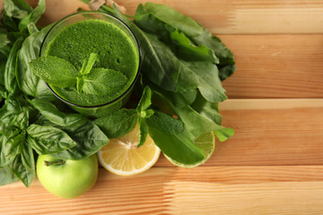 Green healthy juice with fruits and herbs on wooden table close up