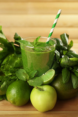 Green healthy juice with fruits and herbs on table close up