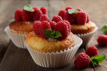 Delicious cupcakes with berries and fresh mint on wooden table close up
