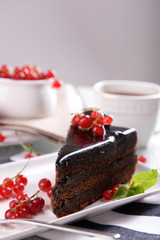 Tasty chocolate cake with berries and cup of tea on table close up