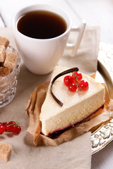 Tasty cheesecake with berries and cup of tea on table close up