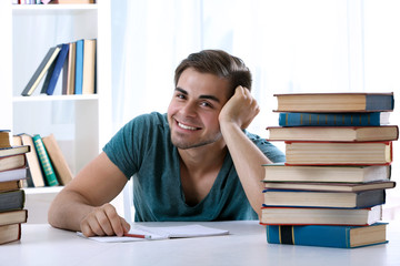 Young man reading book at table in room