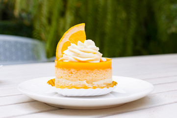 Orange cake on white plate and wooden table with cream and a pie