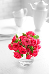 Beautiful flowers in vase on table, on light background