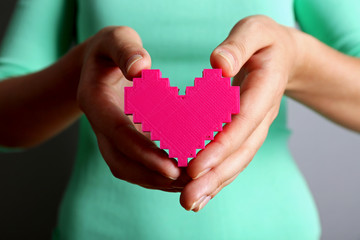 Closeup of plastic puzzle heart in female hands