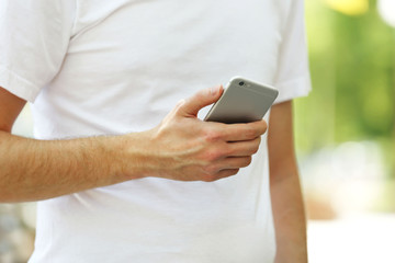 Man holding smart mobile phone outdoors