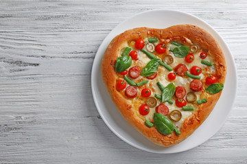 Delicious heart shaped pizza on wooden background