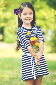 Happy little girl with flowers in the park