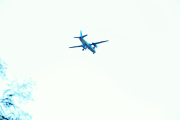 A grey airplane flying on a clear pale blue sky background