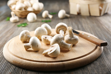 Champignon mushrooms and a knife on wooden background
