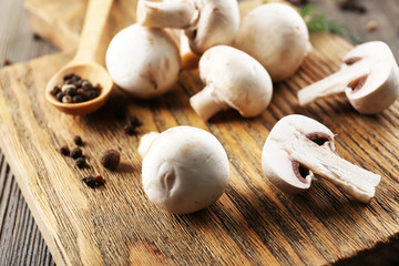Champignon mushrooms, a spoon and spices on wooden background
