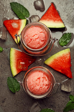 Watermelon ice cream in glass jars on dark background