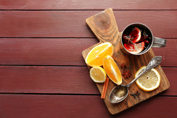 Mulled wine in a mug with citruses on wooden background