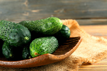 Fresh cucumbers in rustic bowl on  wooden background