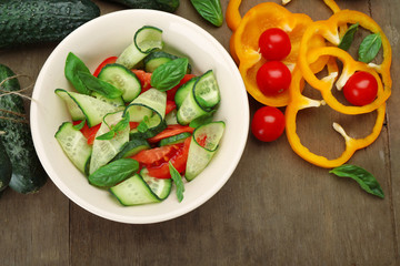 Vegetable salad with cucumbers and pepper on wooden background