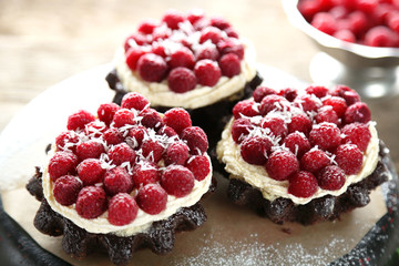Sweet cakes with raspberries on wooden table background
