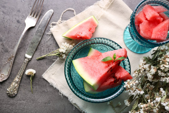 Fresh sliced watermelon in a blue glass bowl on decorated background