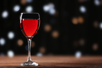 Wine glass on wooden table against defocused lights background