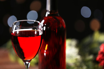 Wine glass with bottle on blurred background, close up
