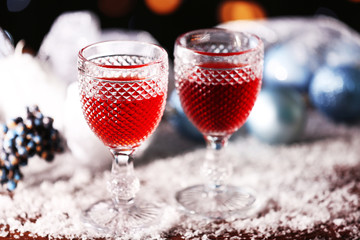 Wine glasses with Christmas decorations on snowy table, close up
