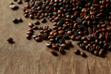 Aromatic coffee beans scattered on wooden background
