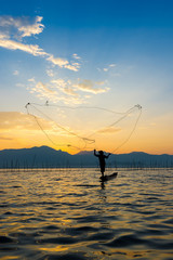 Silhouettes of the traditional fishermen throwing fishing net du
