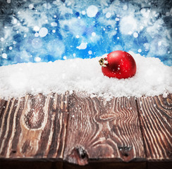 Christmas ball on a wooden table in the snow