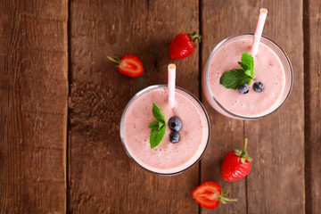 Fresh strawberry yogurt with berries around on wooden background