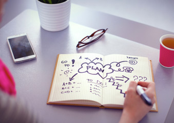 Young woman writes to diary on a white table