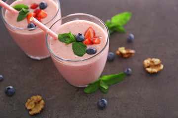 Tasty yogurt decorated with berries, nuts and mint on grey background