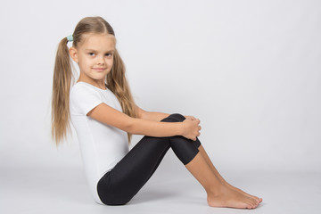 Fototapeta na wymiar Gymnast six years sitting hugging her knees legs