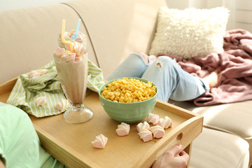 A girl with a tray having lunch on a sofa, close-up