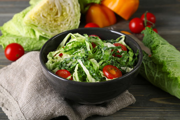 Savoy cabbage and tomato salad served in bowl on wooden table