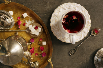 Cup of rose tea with sugar on wooden table