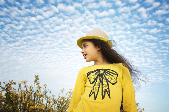 Happy child in spring field. Young girl relax outdoors. Freedom concept