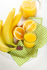 Bananas, oranges and juice on green checkered napkin